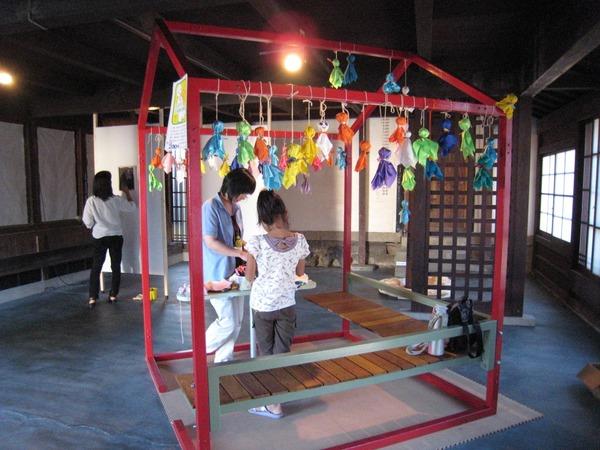 沢山のカラフルなてるてる坊主がつるされて、親子で作っている写真