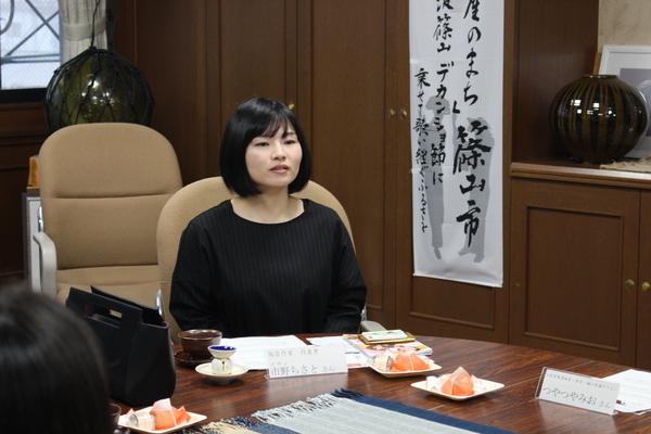 茶色と白色のコーヒーカップセットを目の前に説明をしている市野 ちさとさんの写真