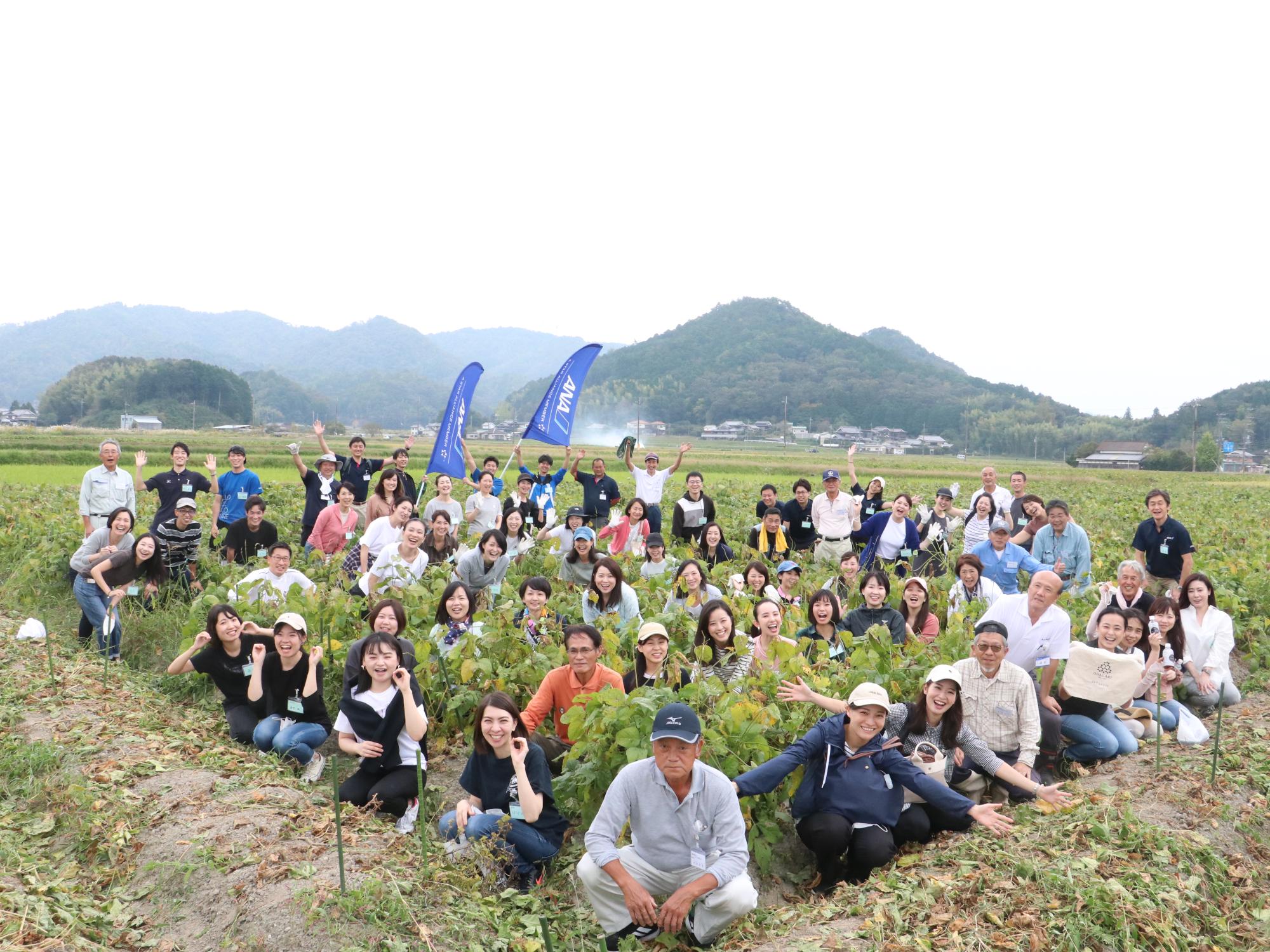 黒枝豆の畑で、収穫を手伝った関係者の方が記念撮影している