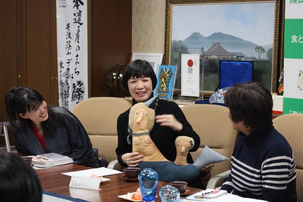 自身が手掛けた造形が専門の人魚をモチーフにしたぬいぐるみを手にしながら説明をするあさうみ まゆみさんの両隣の人が笑顔で聞いている写真