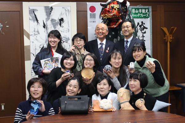 女性芸術家の方が自身で手掛けた作品をそれぞれ手に持って市長も交えた集合写真