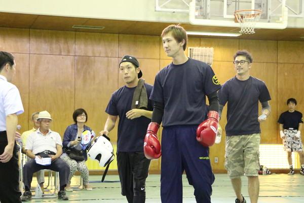 宮田祐樹さんが赤のグローブを付けていて、両サイドに関係者を連れて歩いている写真