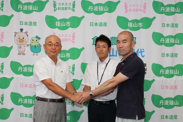 市長、小林智彦主査と河野元秀主事3人で手を取り合っている記念写真