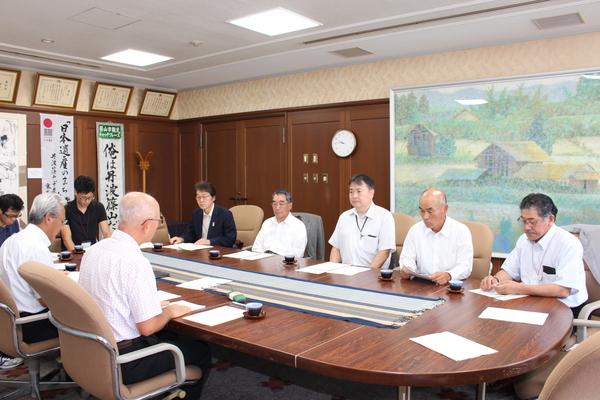 スーツを着た方、9名が会議をしている写真