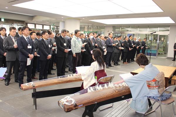 ロビーで琴の演奏に合わせて市歌を斉唱している職員の写真