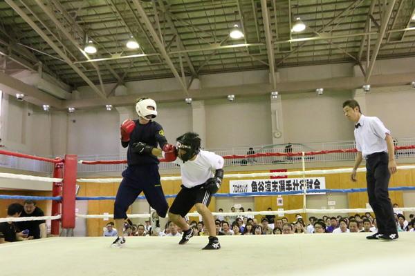 審判が右側にいて、相手が宮田祐樹さんのボディーにパンチするのを、宮田祐樹さんが左パンチしている写真