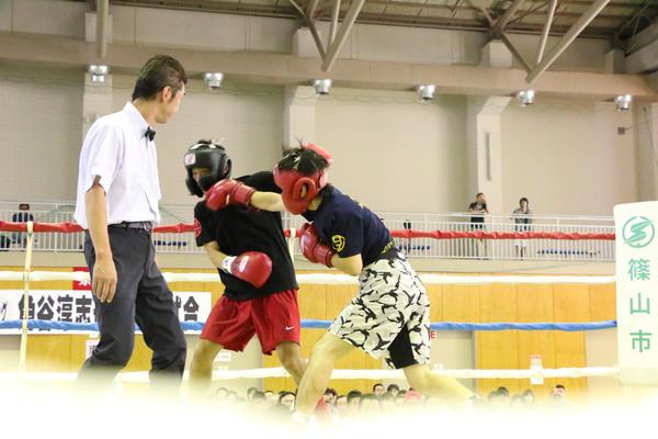 審判が前に立ち、ヘッドギアを付けて、波多野慎也さんが試合をしている写真