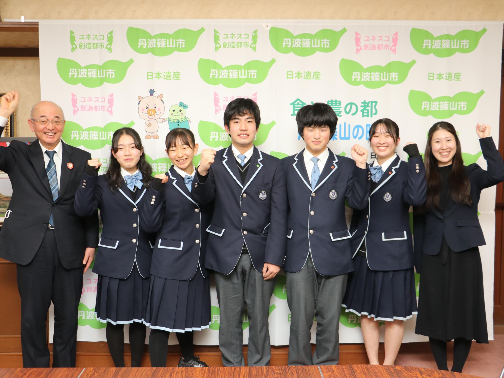 市長と先生、高校生5人がガッツポーズしている