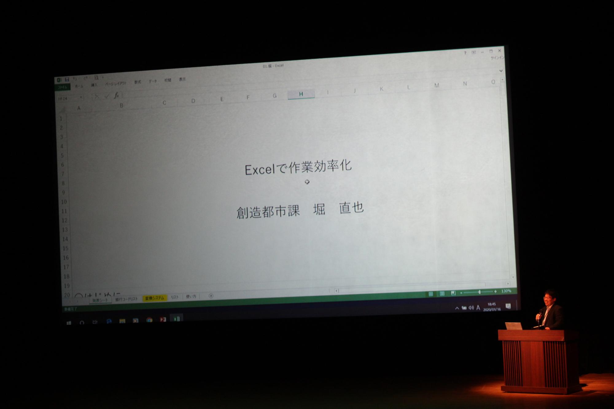 「Excelで作業効率化 」と書かれたスライドと発表者の堀直也さんが説明をしている様子