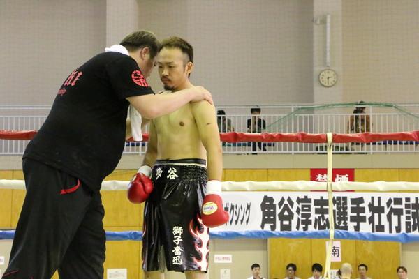 黒いTシャツを着た関係者が角谷選手の正面から肩を組んでいる写真