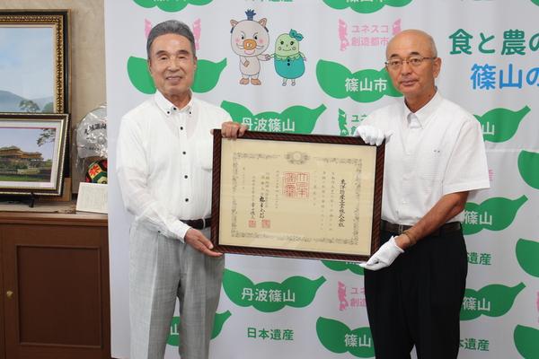 紺綬褒章を受章された東洋物産工業株式会社と市長が額に入った賞状を手に記念撮影している写真