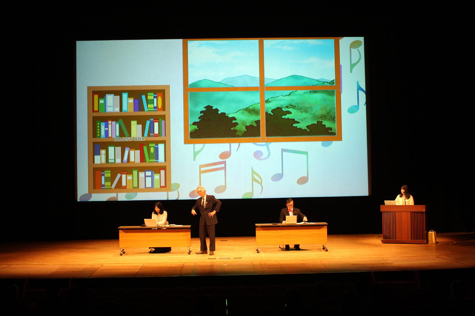 座ってパソコンの画面を見ている秘書に、市長が話しかけている写真