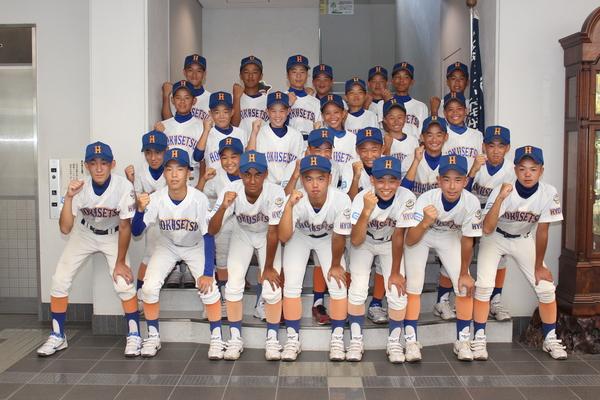 ユニホーム姿の中学生硬式野球チームの選手らが片手ガッツポーズをして記念撮影している写真