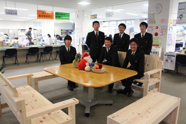 市役所庁内に寄付された木製のベンチ4脚を囲んで設置し生徒3名は座り3名は立って撮影した記念写真