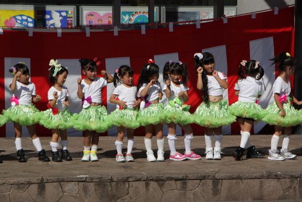 女の子たちが緑色のフリルスカートをはいて、みんなで猫のポーズをしながら踊っている写真