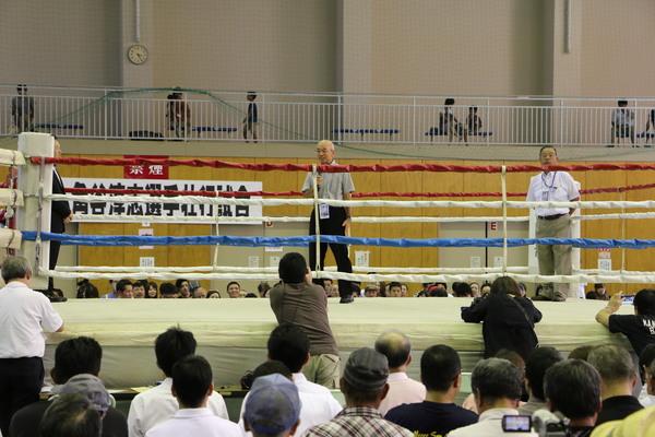 市長がリング上に上がり、マイクを持って観客席に話をしている写真