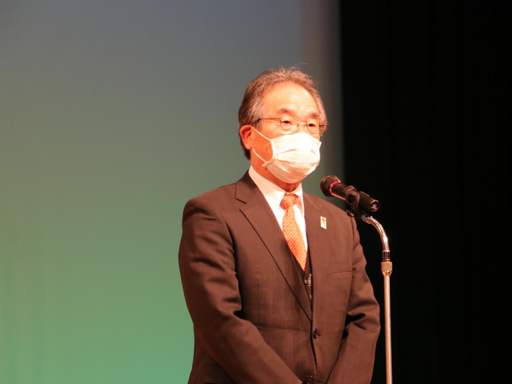 舞台で退任のあいさつをされている