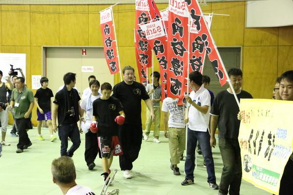 角谷 淳志と書かれた旗を持っている応援の方と同時に角谷 淳志選手が会場入りした様子の写真