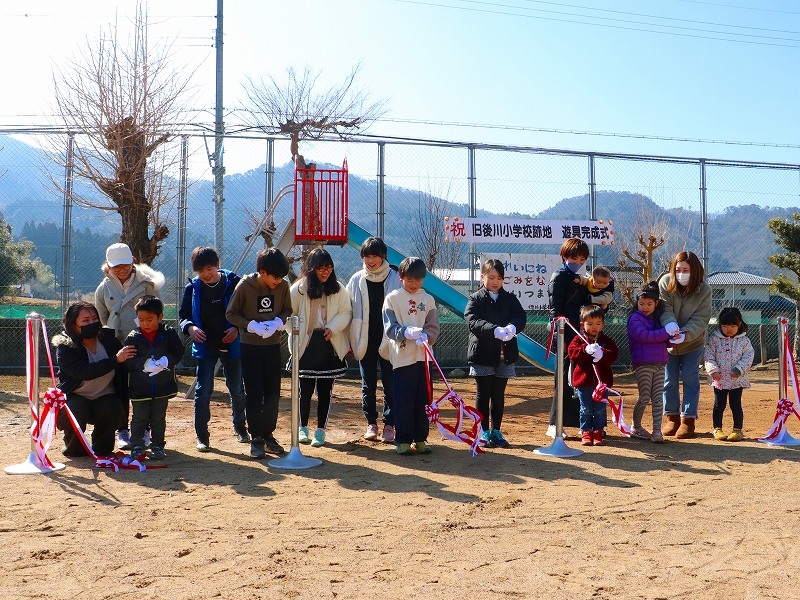 すべり台の前でテープカットするためにこどもたちが並んでいる