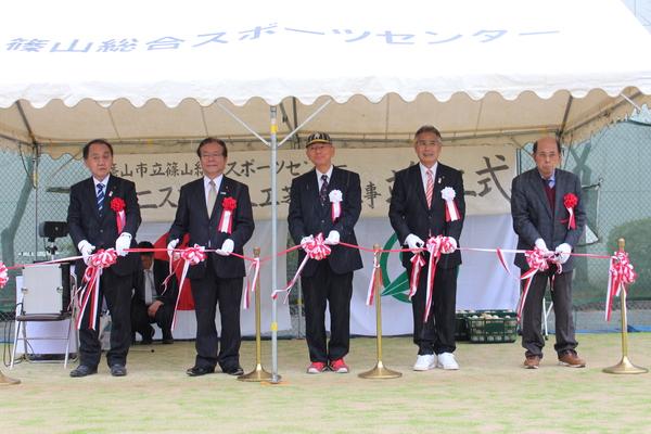 テントの中で市長と4名の男性がテープカットをする記念写真