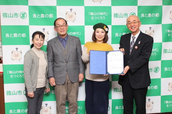 森田 まりこさんと市長が委任状の証書を持っており、お父様、お母様も一緒に記念撮影している写真