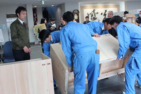 篠山産高土木科3年生が作成したヒノキのカウンターをホールに設置している様子の写真