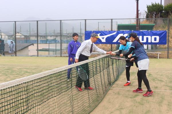 市長がテニスのラケットを持ち対戦相手の女性にボールを渡している写真