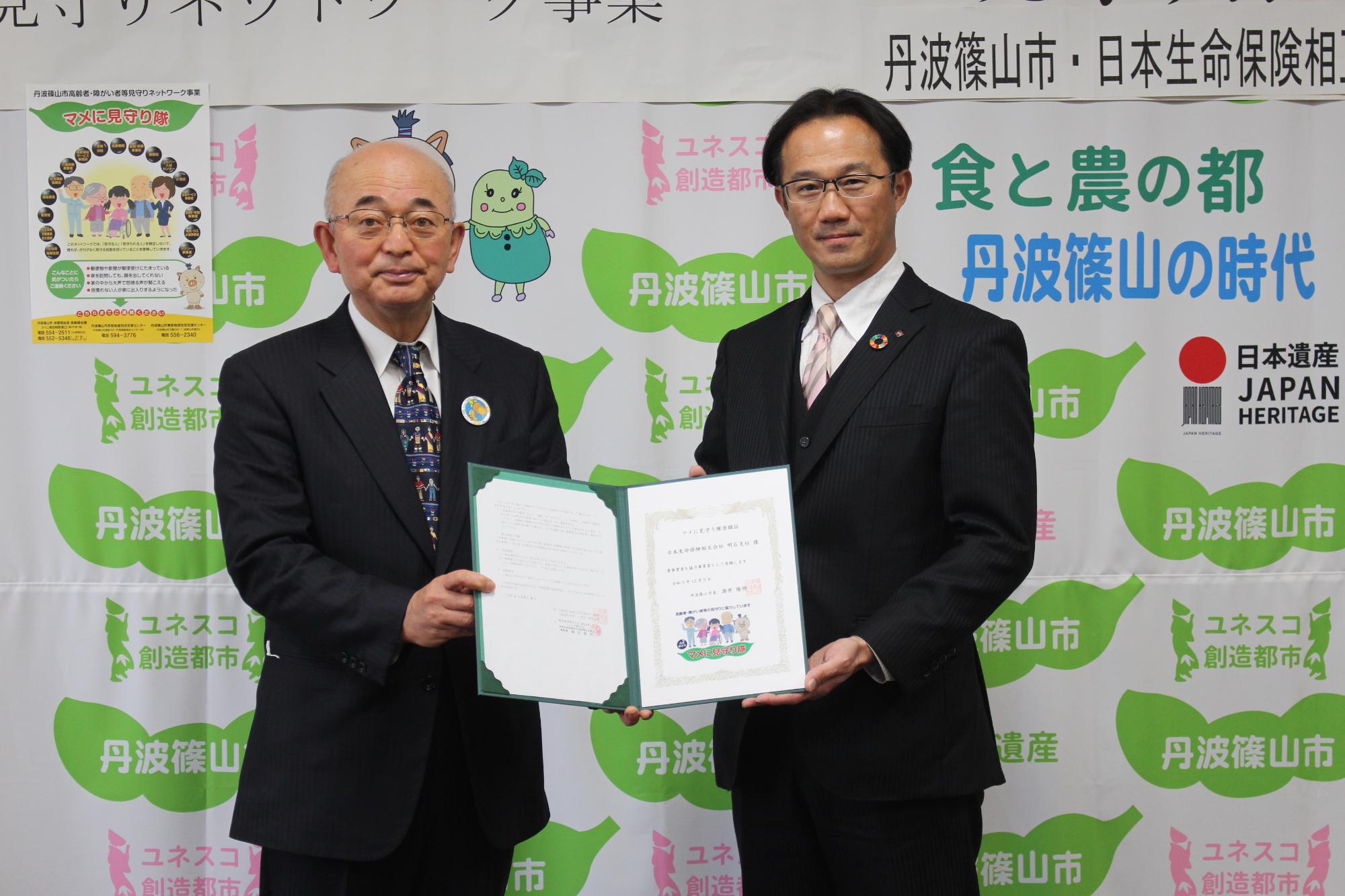 押印された締結書を市長と事業所の社長が一緒に持っている