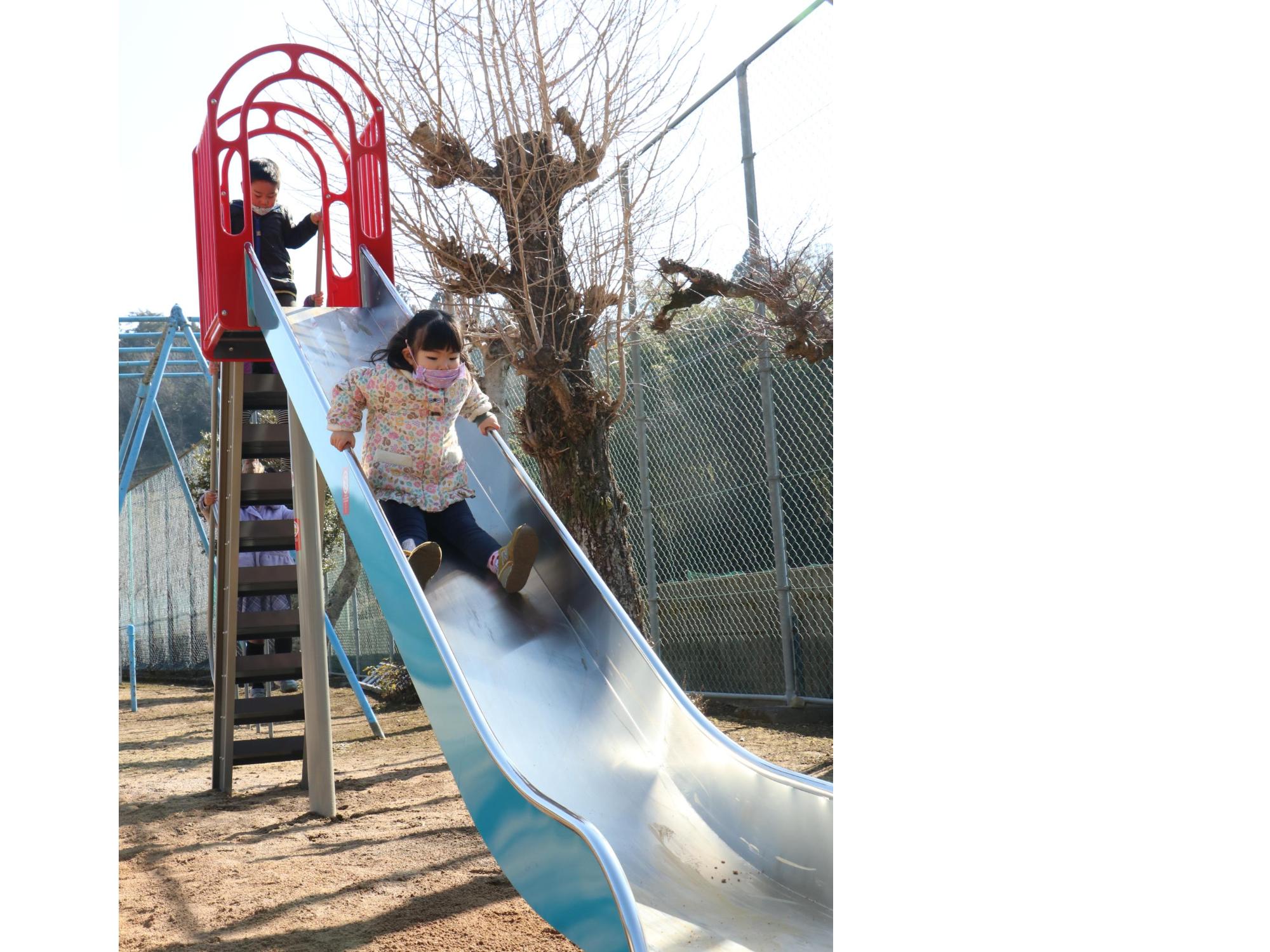 女の子がすべり台をすべっている