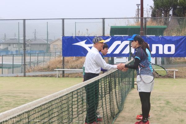 試合が終わり、ネットの前に集まり市長が対戦相手の女性と握手している写真