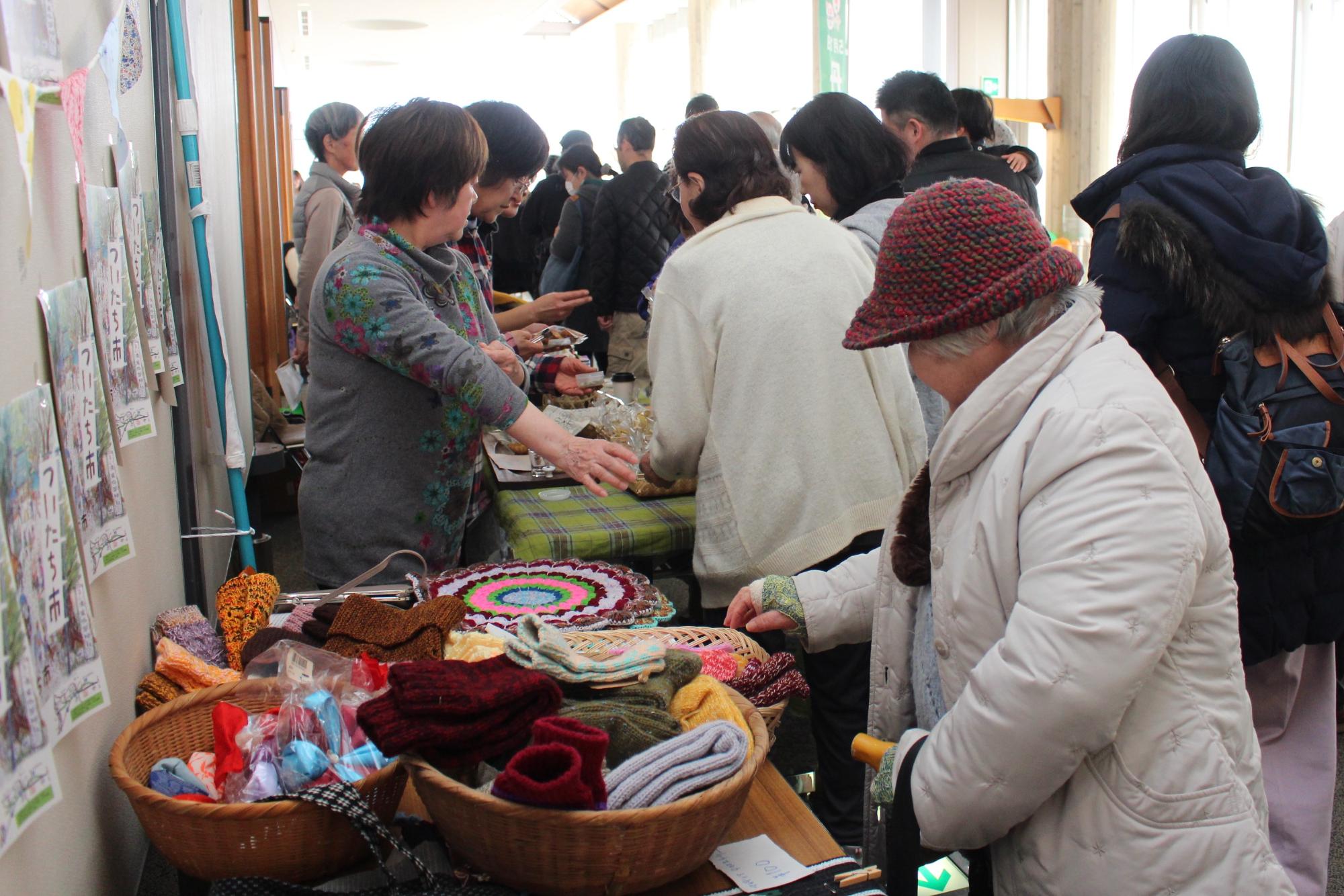 販売されている手袋や食品などを多くの人が見ている写真