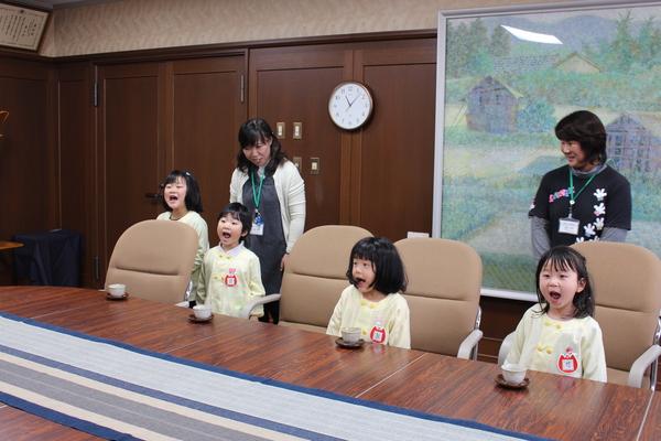 園児達が立ち上がって、大きな口を開けて一生懸命、歌を歌っている様子の写真