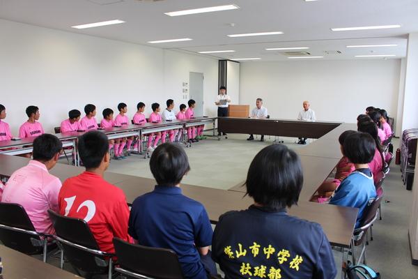 ユニホーム姿の篠山・丹南中学校ホッケー部男女が市長を囲んで長机に座っている写真