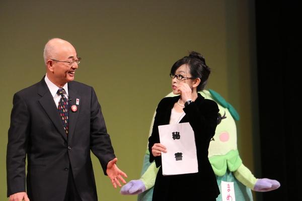 市長が中村秘書と舞台で会話しているのを後ろで見ているゆるキャラの写真