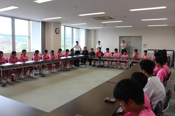 ユニホーム姿の篠山・丹南中学校ホッケー部男女が向かい合わせに長机に座っている写真