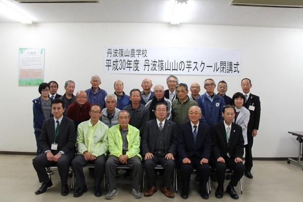 丹波篠山山の芋スクール閉講式と書かれた幕の前で30名ほどの人たちが市長と一緒に記念撮影をしている写真