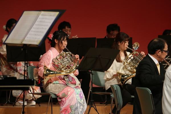 舞台にて晴れ着姿やスーツ姿で楽器を演奏している写真