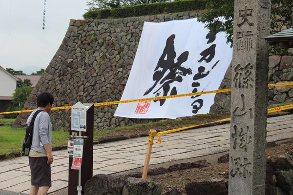 篠山城跡の石垣の所に大きなデカンショ祭と書かれた幕が張られていて案内板のようなものを男性が見ている写真