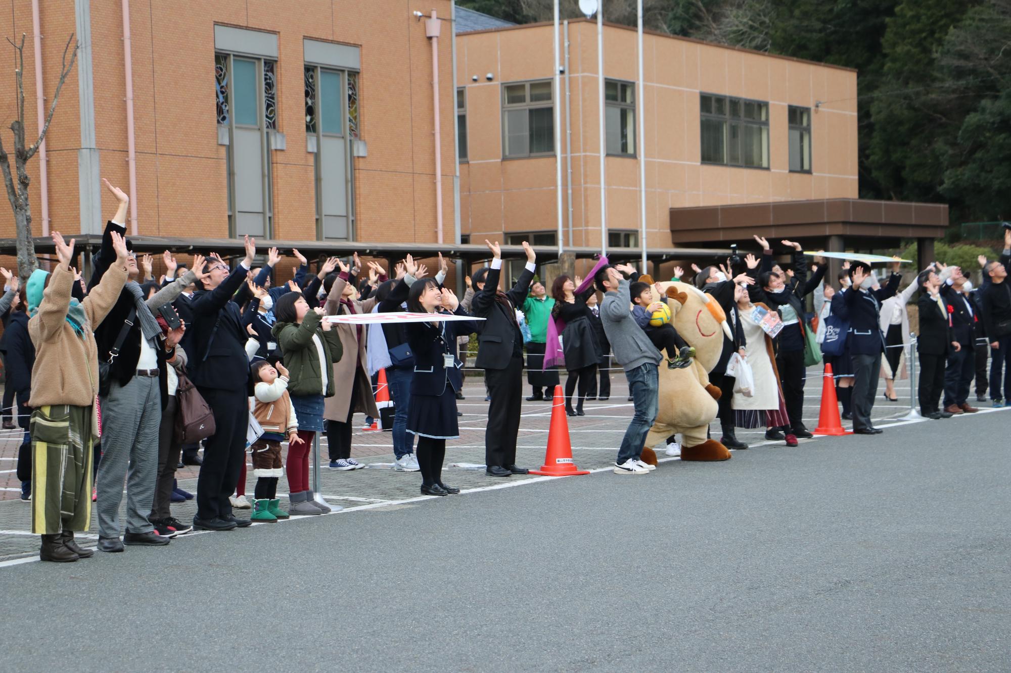 人文字を作っている人々が、上に向かって手を振っている写真