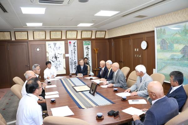 ささやま郵友会の人たちが社会参加章の賞状と盾を机に置き、受賞の報告をしている写真