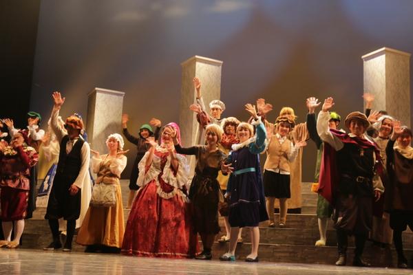 様々な衣装を着たミュージカル出演者が舞台の上から笑顔で手を振っている写真