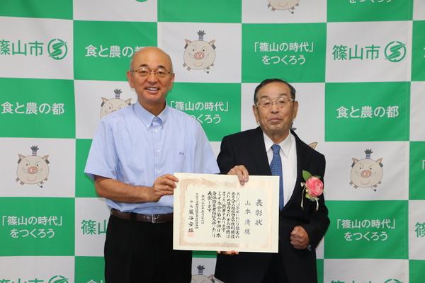 山本 清さんと市長が一緒に表彰状を手に記念撮影している写真