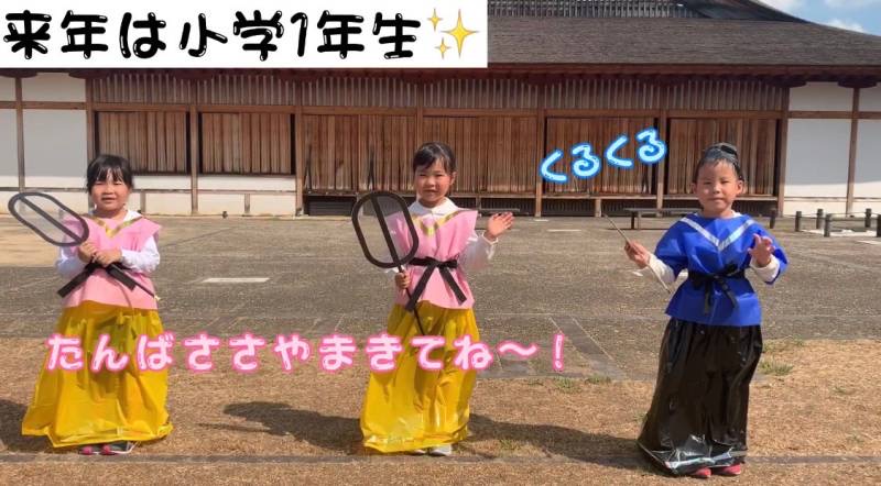 市内幼稚園児3人が古代の服装をして、手を振っている