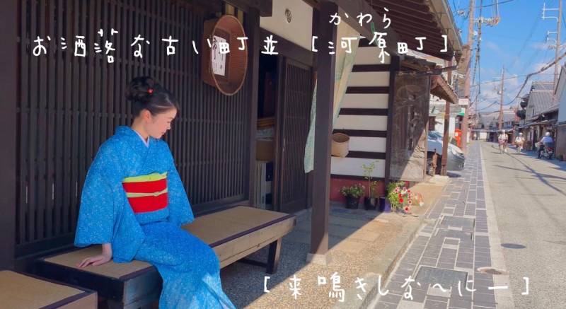 着物を着た女性が河原町のとおりにあるベンチに座りながら万葉集を朗唱している