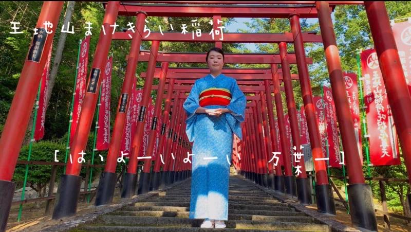 王地山まけきらい稲荷の鳥居前で、着物を着た女性が万葉集を朗唱している