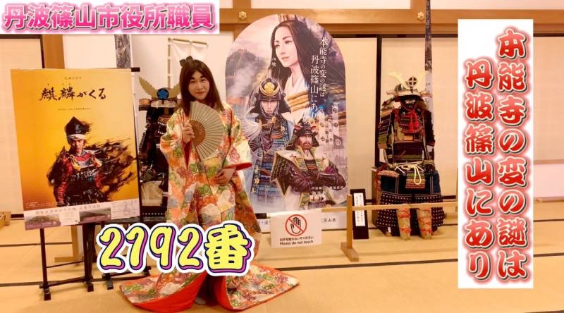 十二単を着て扇子を持った市職員が大書院内の展示室前にいる