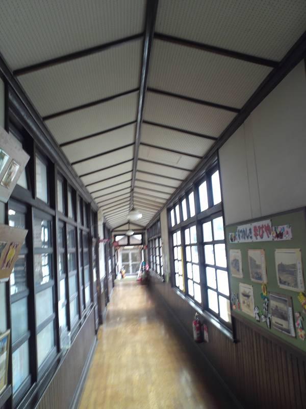 レトロな木造校舎の廊下に光が差し込んでいる写真