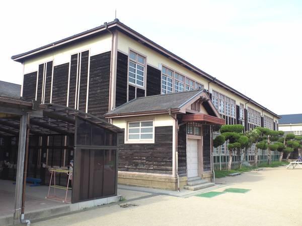 レトロな木造建築の校舎と松の木が植えられている校庭が写っている写真