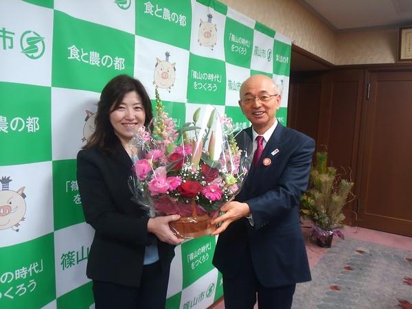 谷掛さんと市長で、お祝いの花を持って記念写真