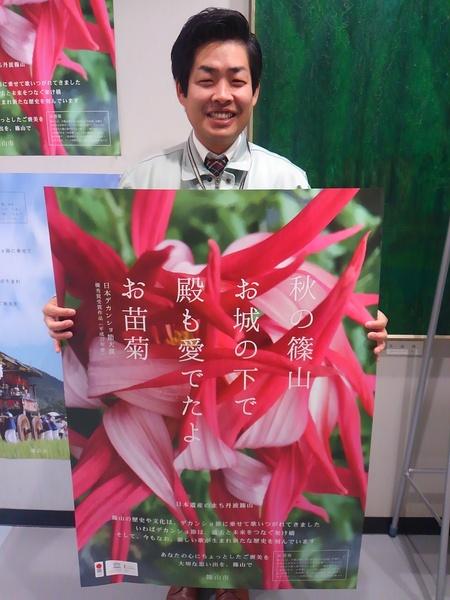 ピンク色のお苗菊の写真の上に「秋の篠山 お城の下で、殿も愛でたよ お苗菊」と書かれたポスターを男性が笑顔で持っている写真